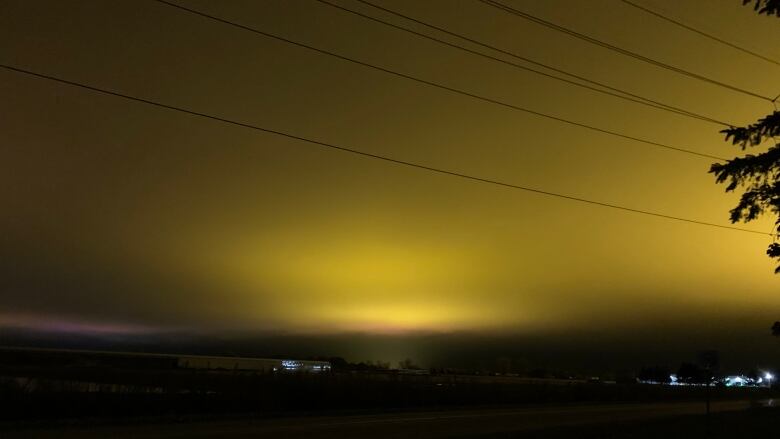 A large golden glow is cast across a night sky