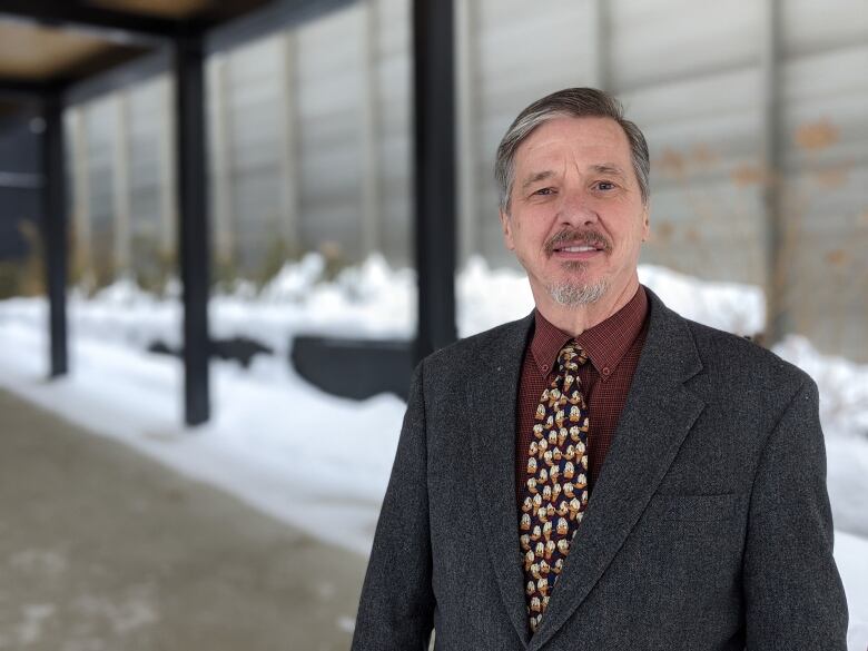 A man in a suit poses outside a building.