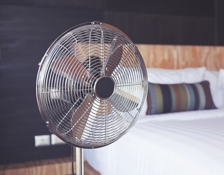 Metal cooling fan on stand in bedroom.