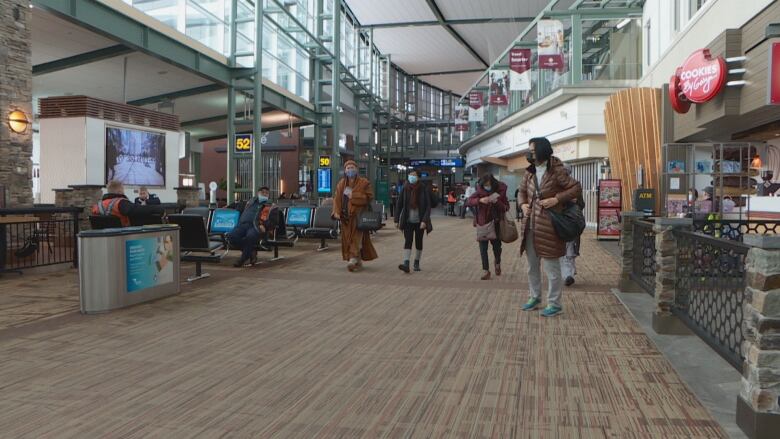 People walk inside a large airport terminal.