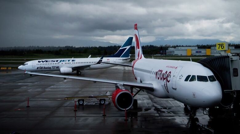 Two airplanes sit on the tarmac at an airport.