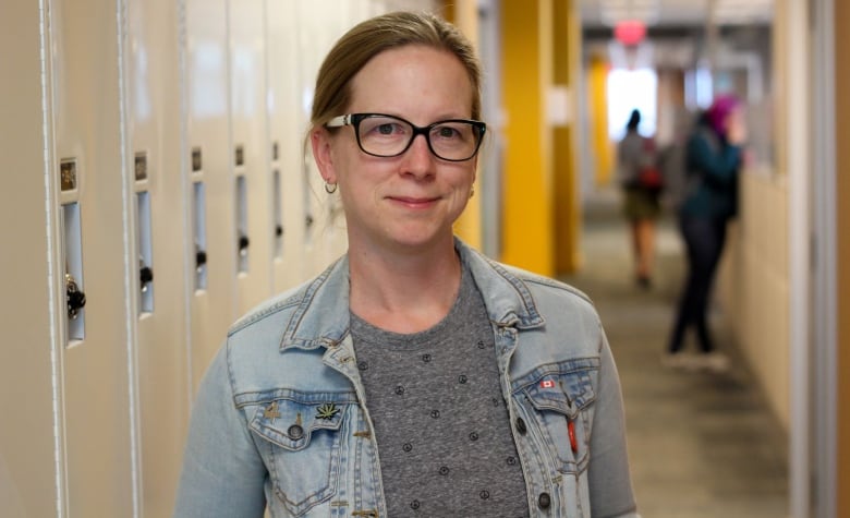 A woman stands in front of lockers.