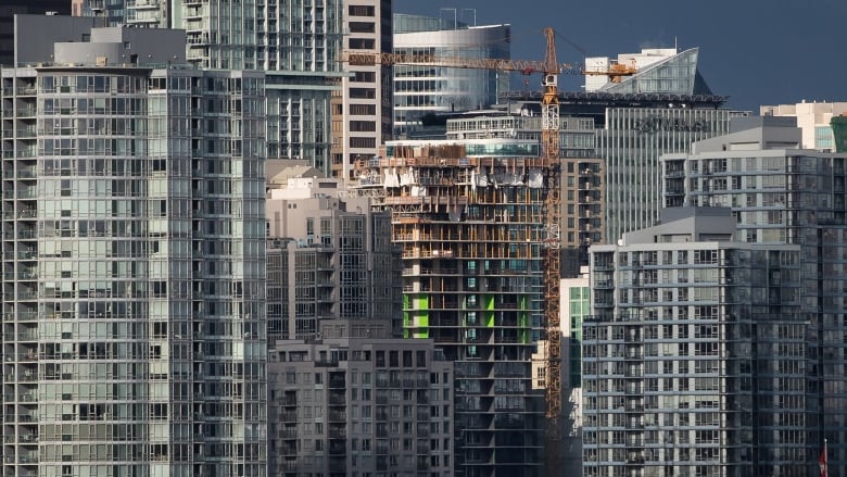 A city skyline with apartment towers including at least one with a crane that is under construction