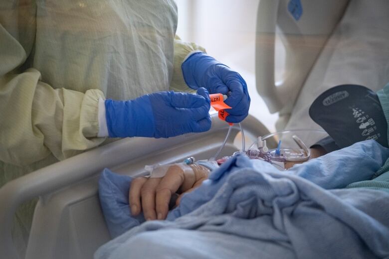 A nurse tends to a patient suspected of having COVID-19 in an intensive care unit.