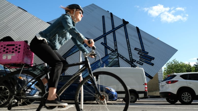 A woman cycles past the Royal Ontario Museum in a protected bike lane on Bloor Street West.