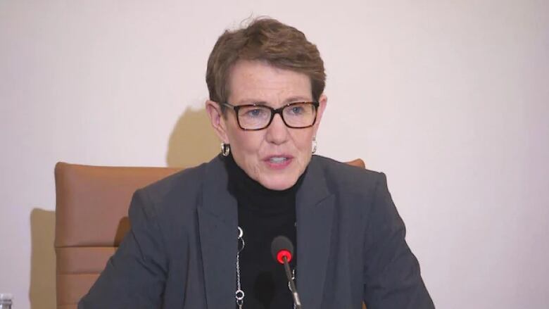 A woman with short hair speaking at a microphone.