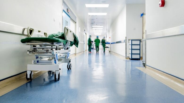 Empty hospital hallway with a stretcher on the left side.