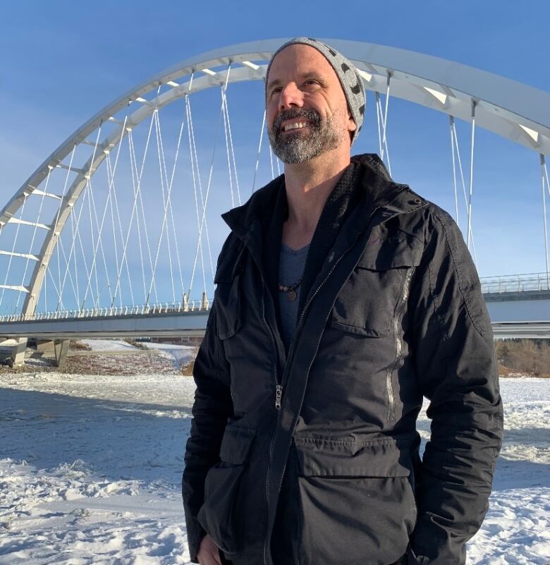 A man stands in front of the Walterdale Bridge.