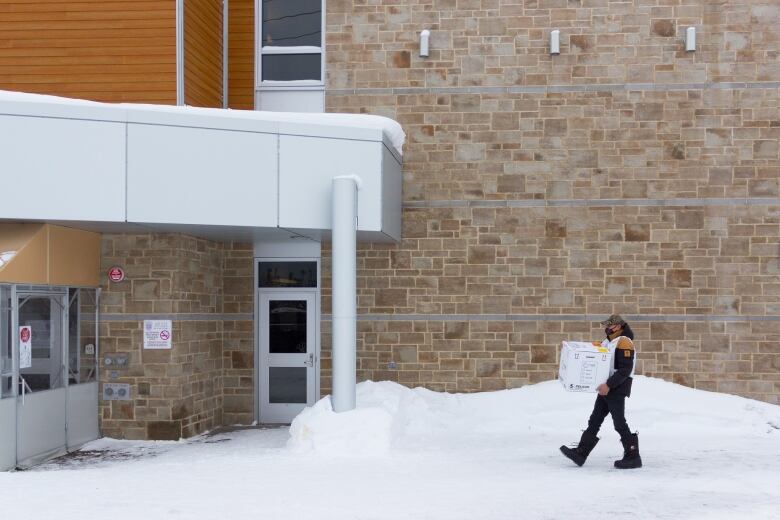 A man carry a box to a health clinic building.