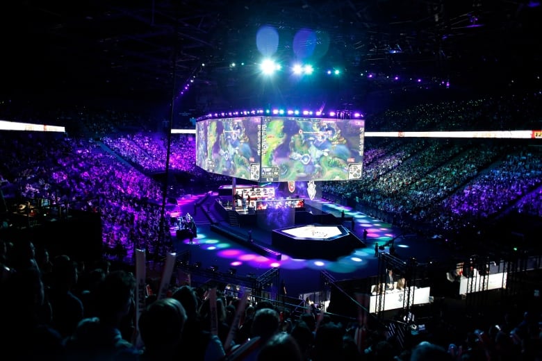 A large arena with a big screen showing video games.