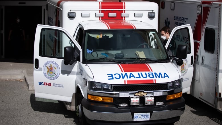 A paramedic is seen getting into a parked B.C. ambulance that has both doors open.