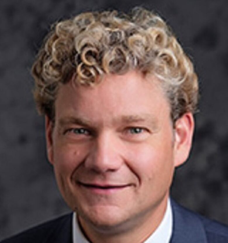 Portrait of a man with curly blonde hair and a bow tie. 