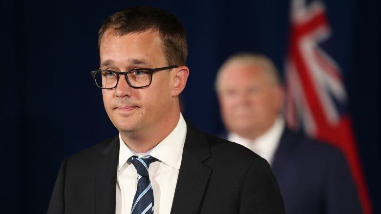 A man in a suit speaks at a press conference.