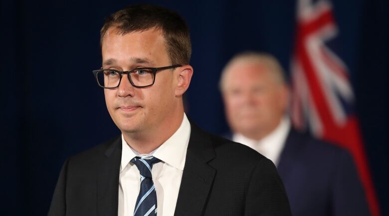 A man in a suit speaks at a press conference.