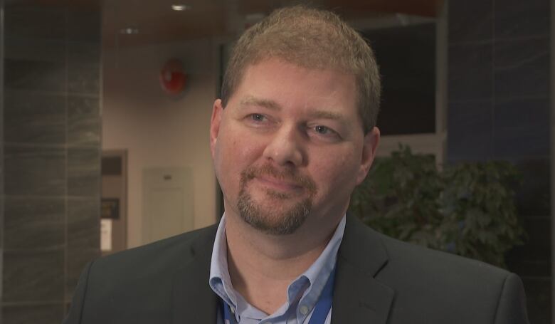 A man wearing a suit stands in an office space.