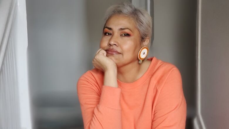 A woman in an orange shirt poses for a photo.