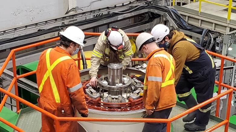 Workers look at a mechanical issue on a generator.