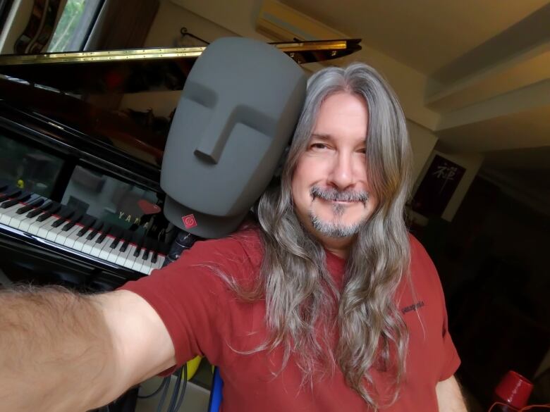 A man takes a selfie in front of a piano.