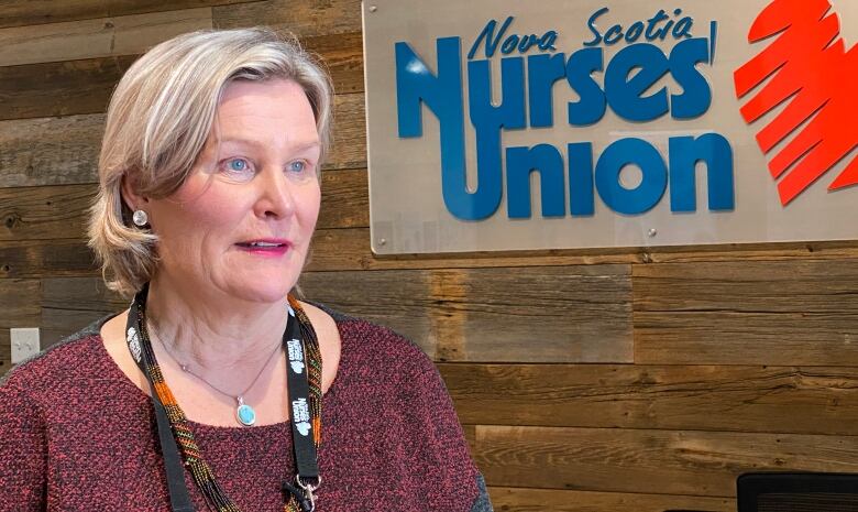 A woman stands in front of a sign saying Nova Scotia Nurses' Union. 