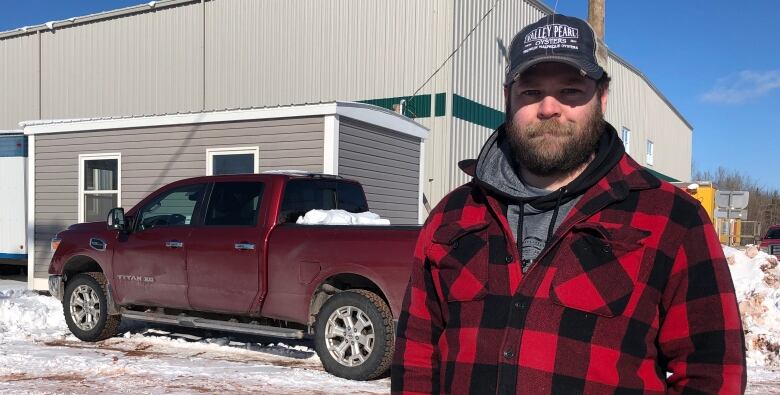 Tyne Valley Mayor Jeff Noye stands in a red plaid jacket smiling with his hands in his pockets.