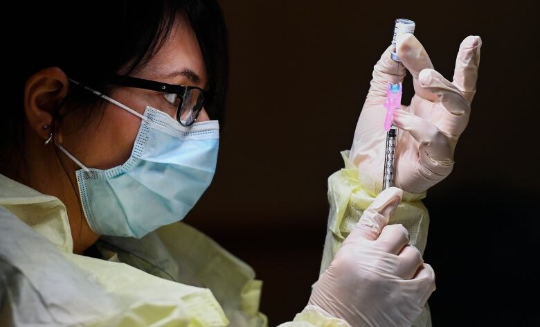 Francesca Passer, a registered pharmacist technician, prepares a dose of the Pfizer-BioNTech COVID-19 vaccine at a vaccination clinic in Toronto. 