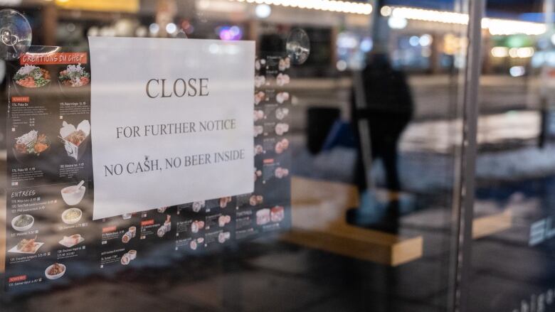 A sign on a sushi store says closed for further notice. No cash, no beer inside.