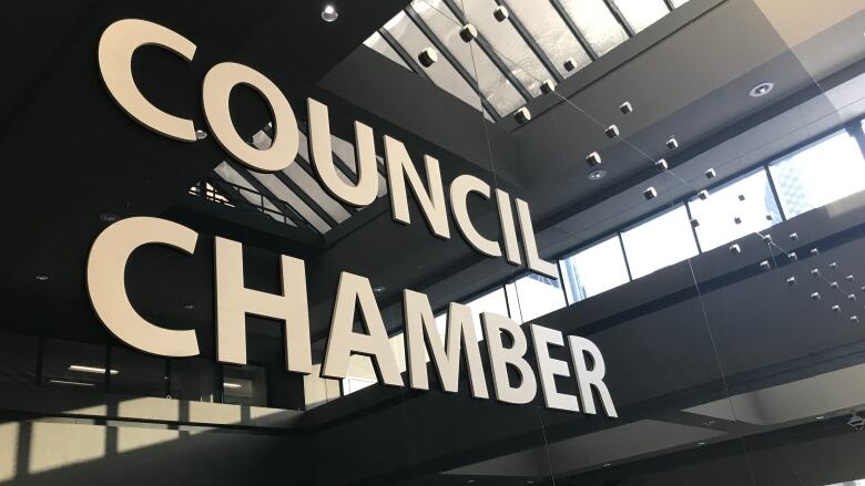 The words COUNCIL CHAMBERS appear in all caps on a polished stone wall at Calgary City Hall.