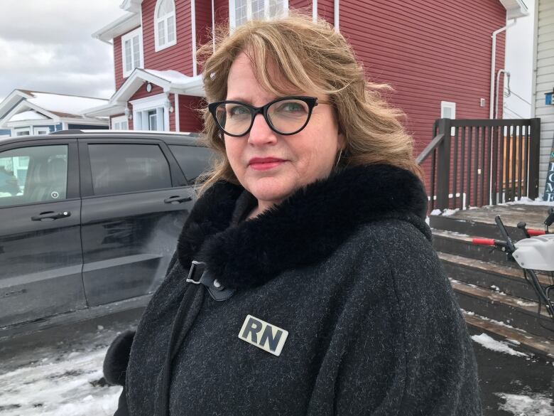 A woman in glasses stands outside