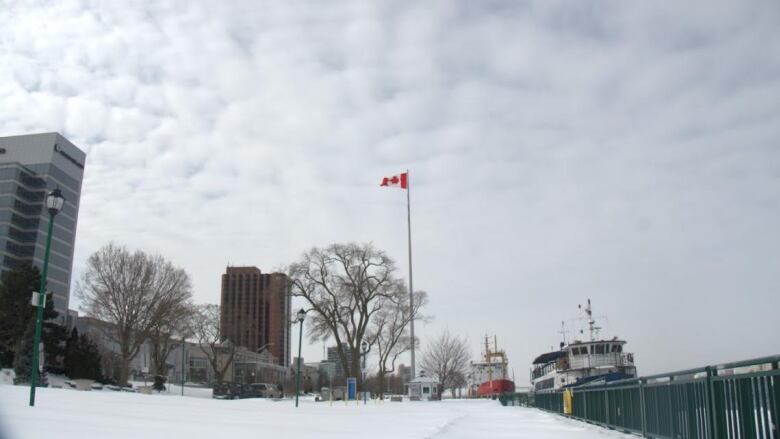 A snowy riverfront with a big Canadian flag.