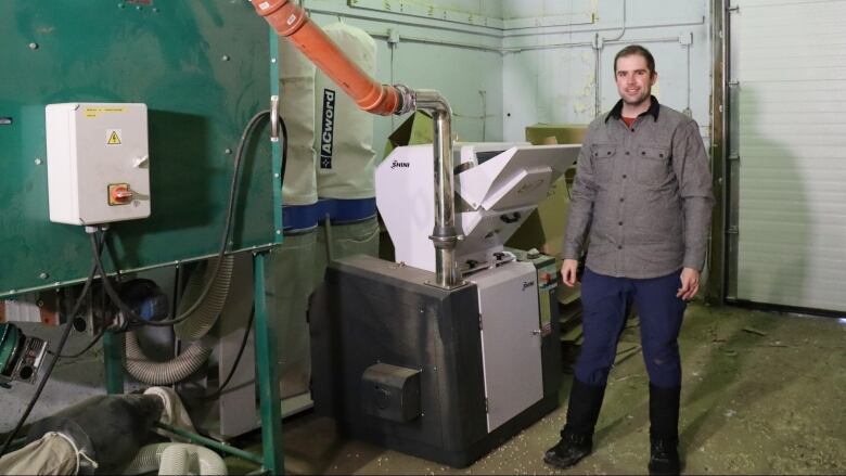 A man stands next to an industrial machine. 