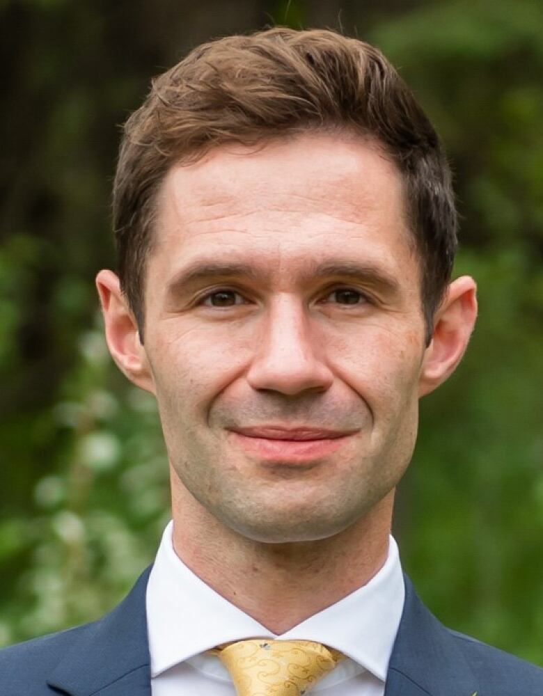 A close-up portrait shot of a man smiling for the camera.