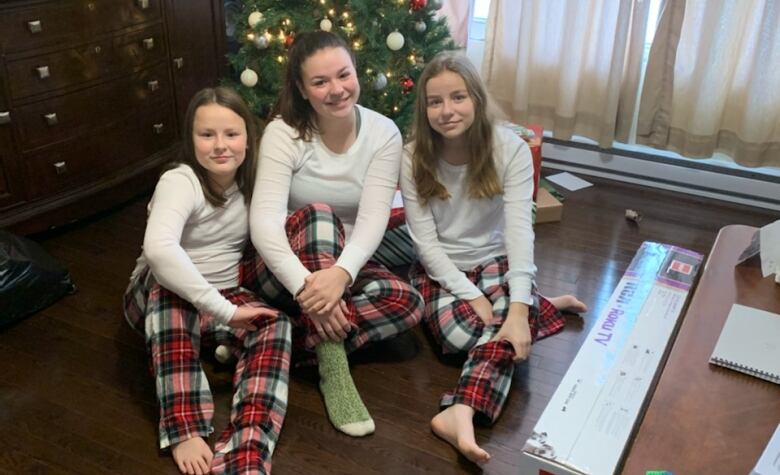 Three girls sitting on the floor in matching Christmas pjs. 