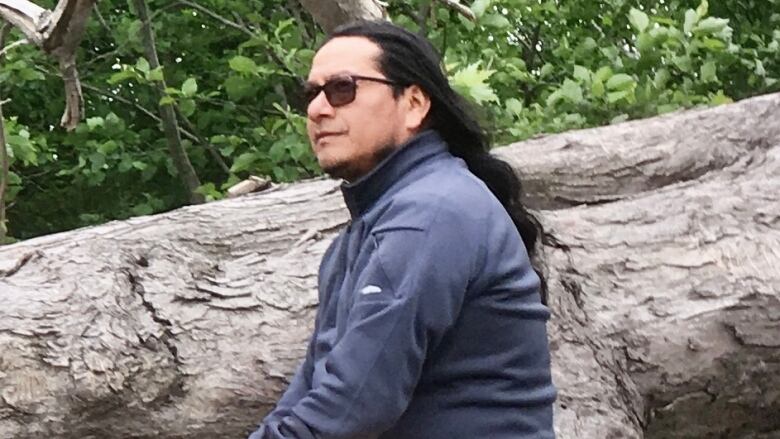 Jeremias Tecu sits on a tree branch to pose for a photo.