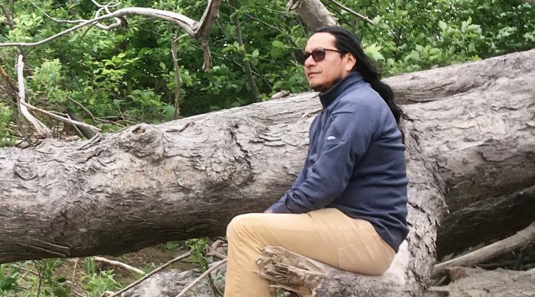 Jeremias Tecu sits on a tree branch to pose for a photo.