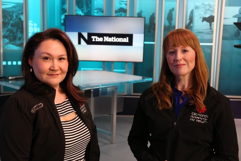 Two people in CBC North jackets stand together in a newsroom.