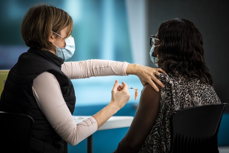 A registered nurse delivers a Pfizer COVID-19 vaccination to a front-line worker at Vancouver General Hospital in Vancouver, British Columbia on Thursday, March 4, 2021. 