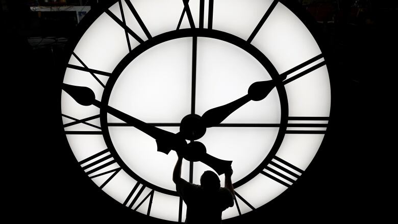 A person turns the hands of a giant clock.