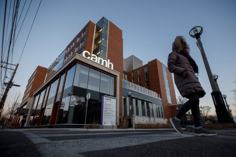 Photograph of exterior showing a woman in a jacket working past the Centre for Addiction and Mental Health (CAMH) Queen Street campus