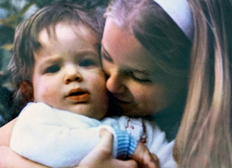 Photo of a teenage girl with long blonde hair hugging a baby with short brown hair.