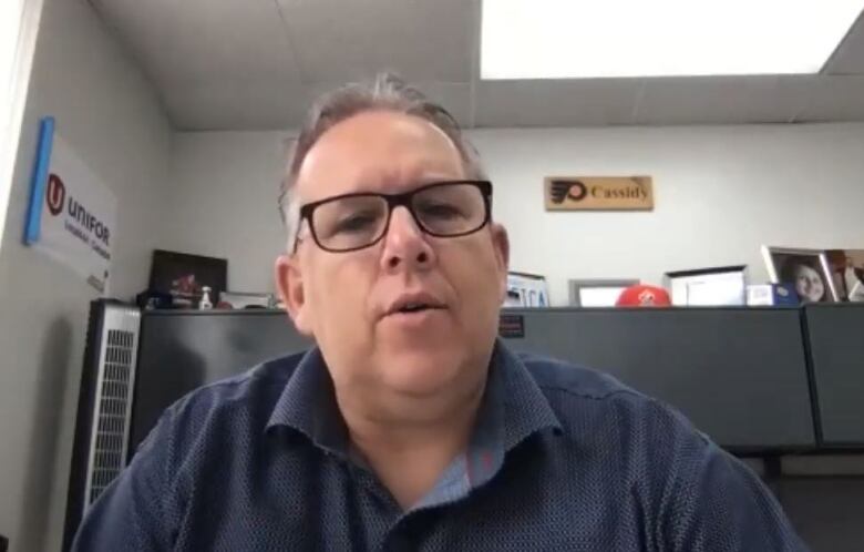 Picture of a man at his desk with cupboards in the background.