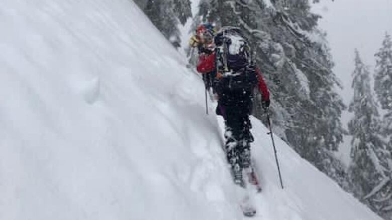 A skier skis across a steep mountain