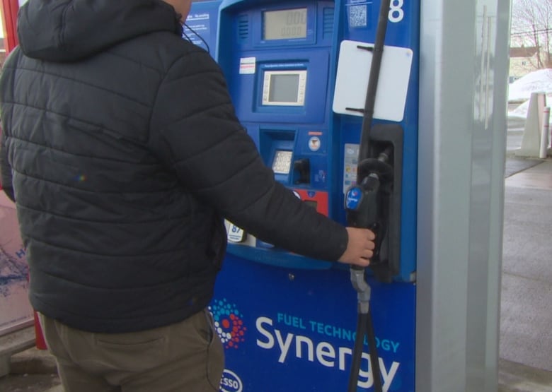 A man reaches for a gas pump.