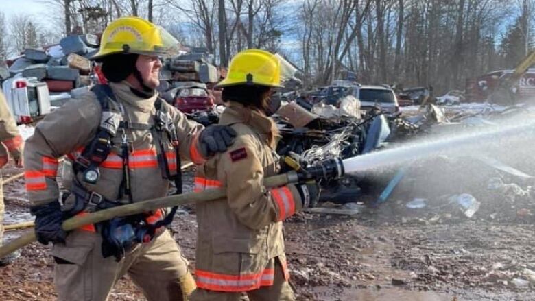 Two firefighters in a practice yard with a hose.