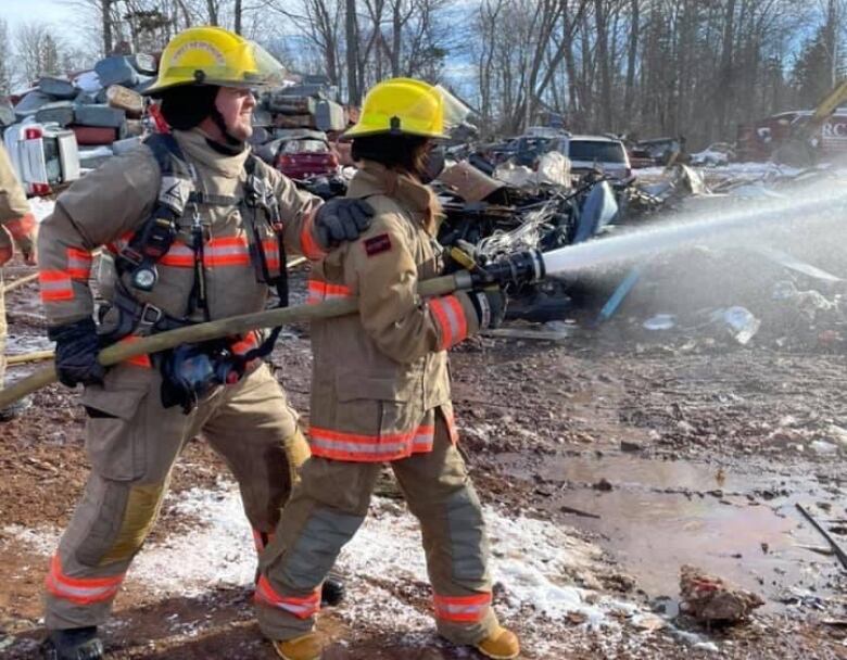 Two firefighters in a practice yard with a hose.