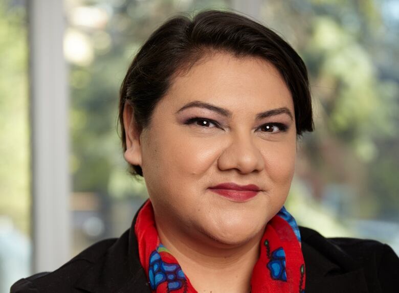 A woman in a red scarf smiles at the camera. 