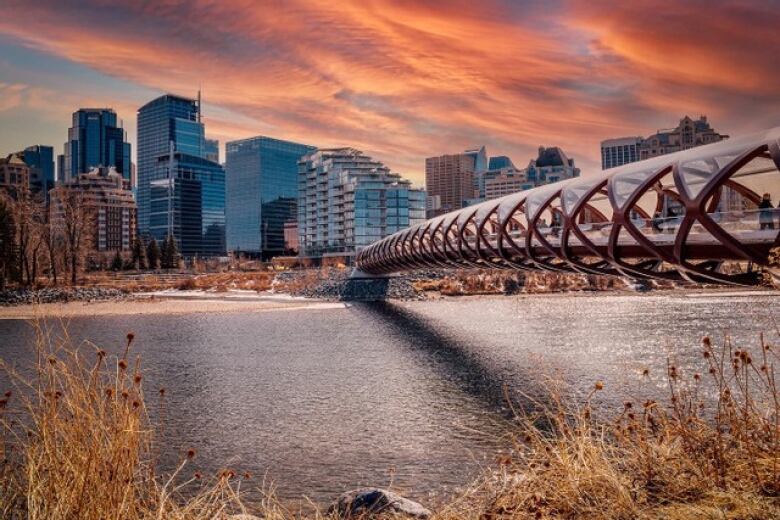 A straight-span red pedestrian bridge to downtown Calgary, as seen at sunset.