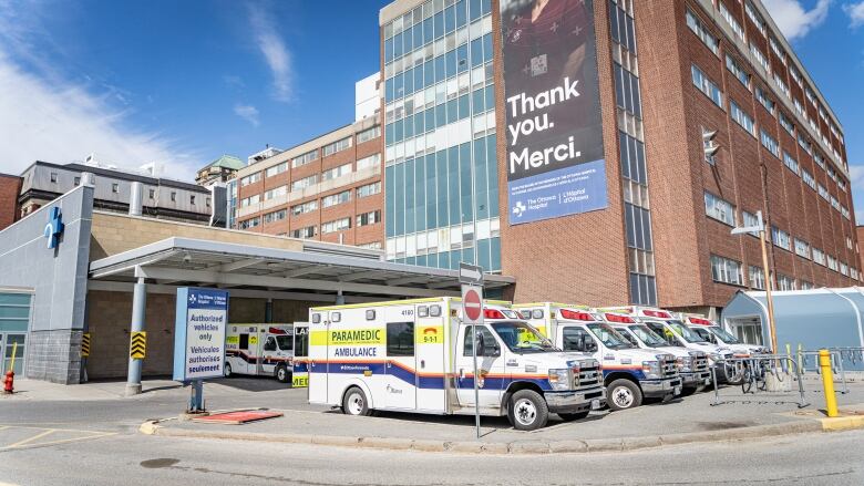 Several ambulances parked outside a hospital on a sunny day.