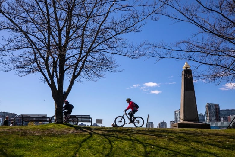 Two cyclists ride along the Stanley Park seawall in Vancouver, B.C.