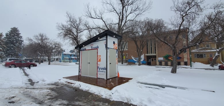 a community fridge structure sits in a parking lot in winter