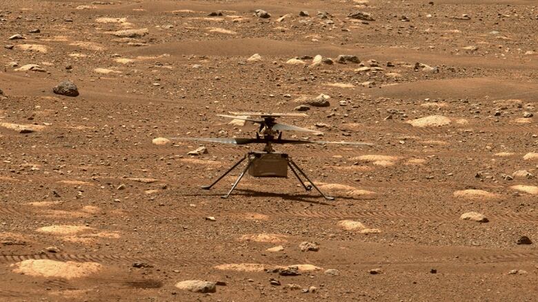 The helicopter sits on top of the red Martian surface.